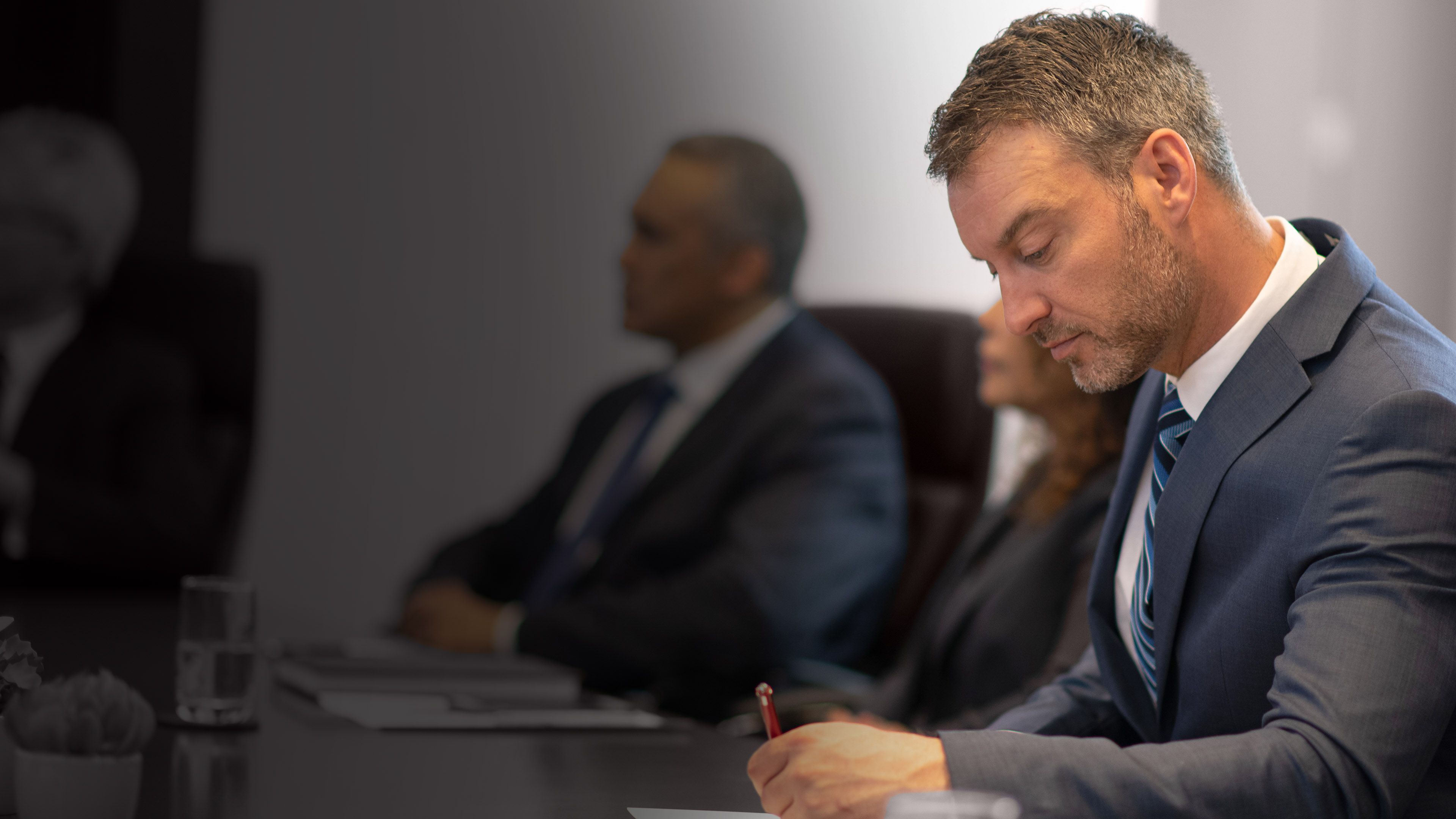 Executive taking notes during a leadership meeting, representing succession planning and future-ready talent decisions.