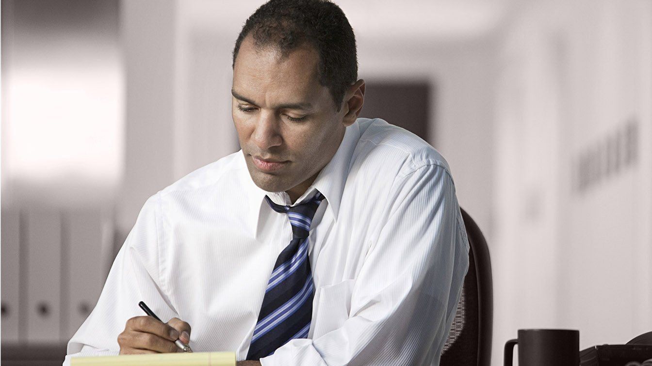 Image for RHR’s About Us and Careers section featuring a professional man writing notes at his desk in an office environment, representing focus, thoughtful leadership, strategic thinking, and professional growth at RHR.