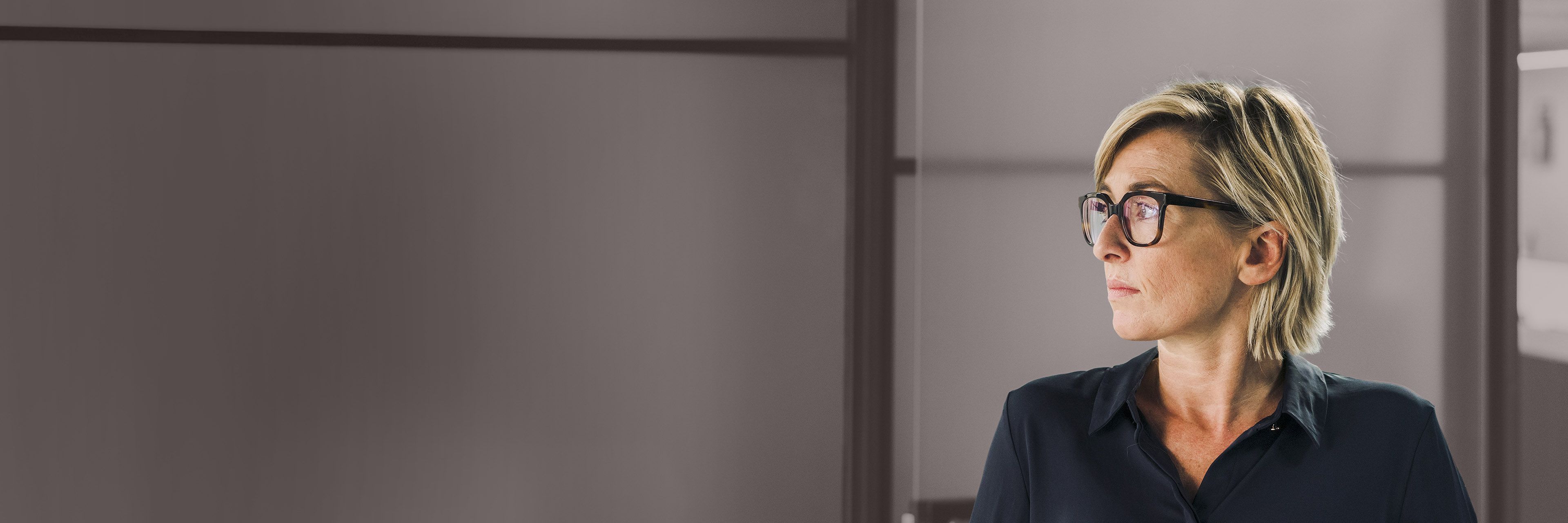 Executive wearing glasses in an office setting, representing thoughtful leadership, focus, and strategic decision-making.