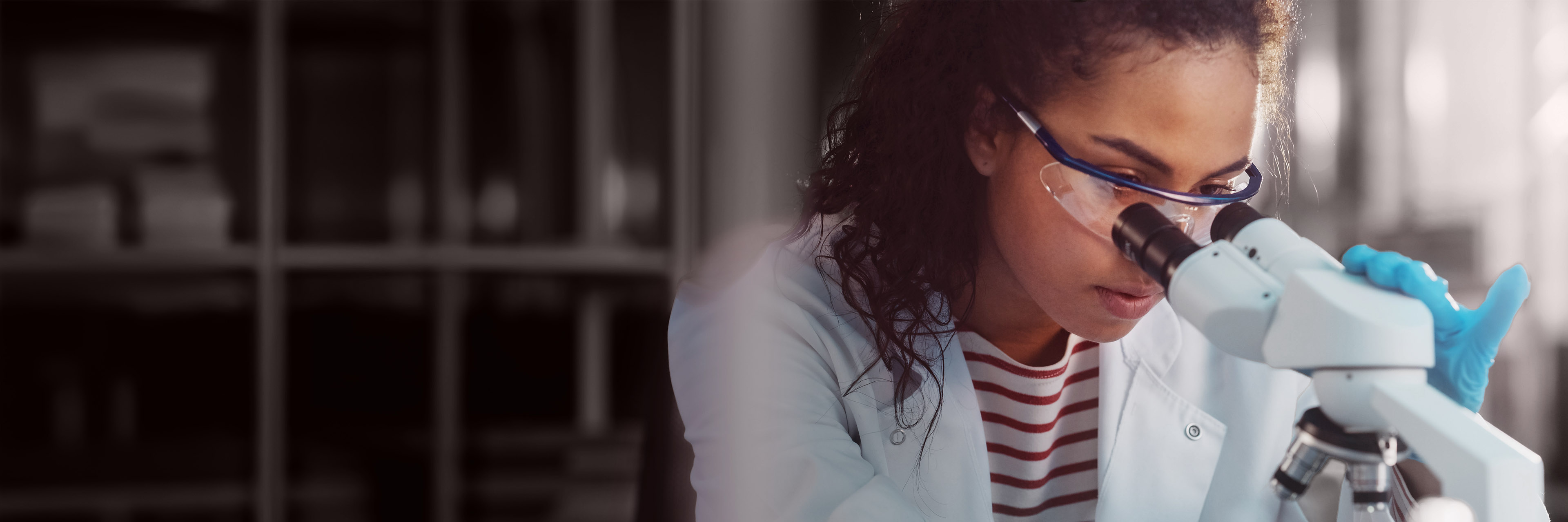Research professional using a microscope, representing executive assessment, leadership coaching, and data-led talent development.