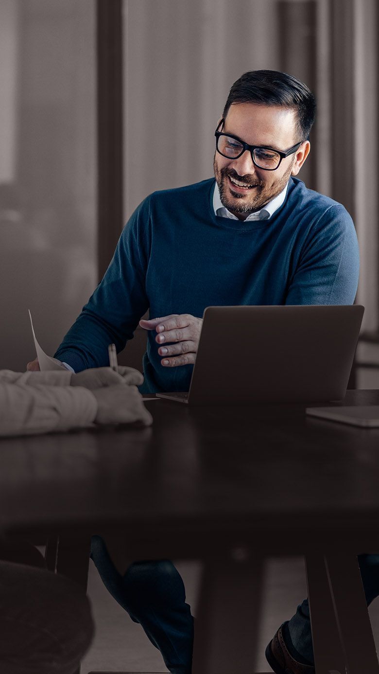 A professional collaborating at a conference table with a laptop, representing executive coaching, leadership development, and business partnership.