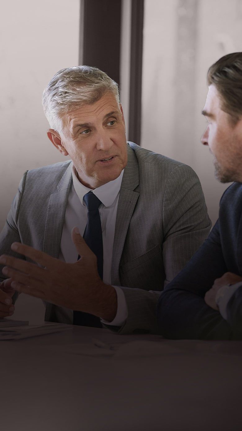 Two executives in discussion during a business meeting, representing executive coaching, strategic leadership, and collaborative decision-making.