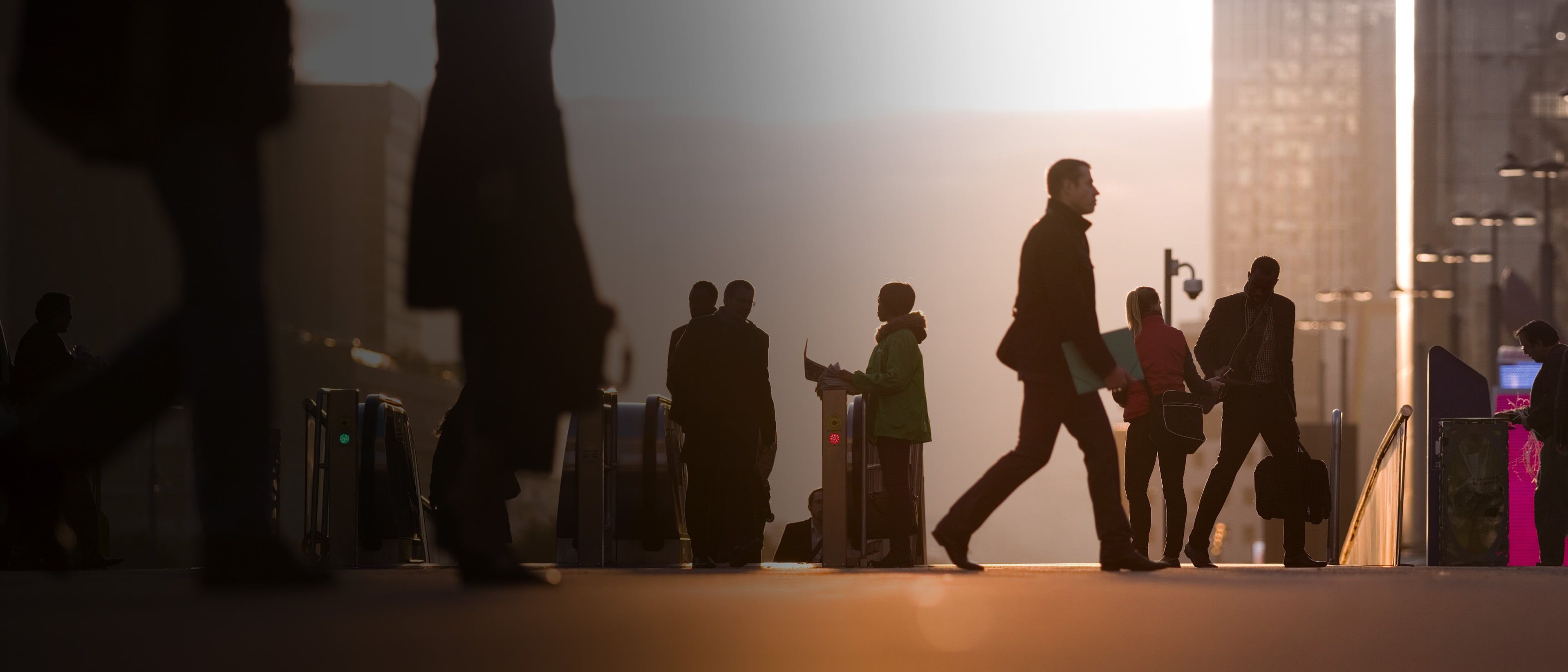 Silhouetted professionals walking outside modern city office buildings during sunset, representing early-career private equity dealmakers.
