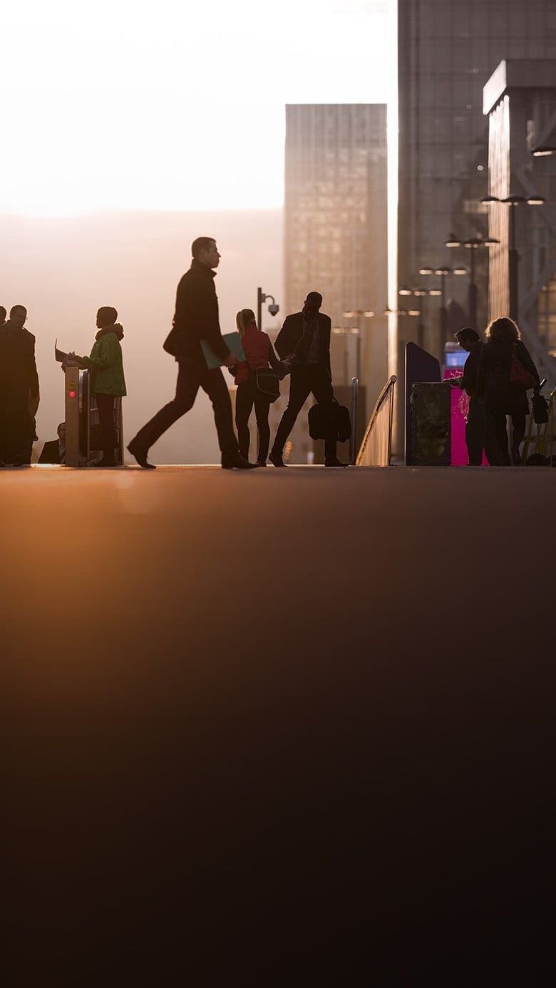 Silhouetted corporate professionals commuting past modern office towers, reflecting emerging talent in PE.