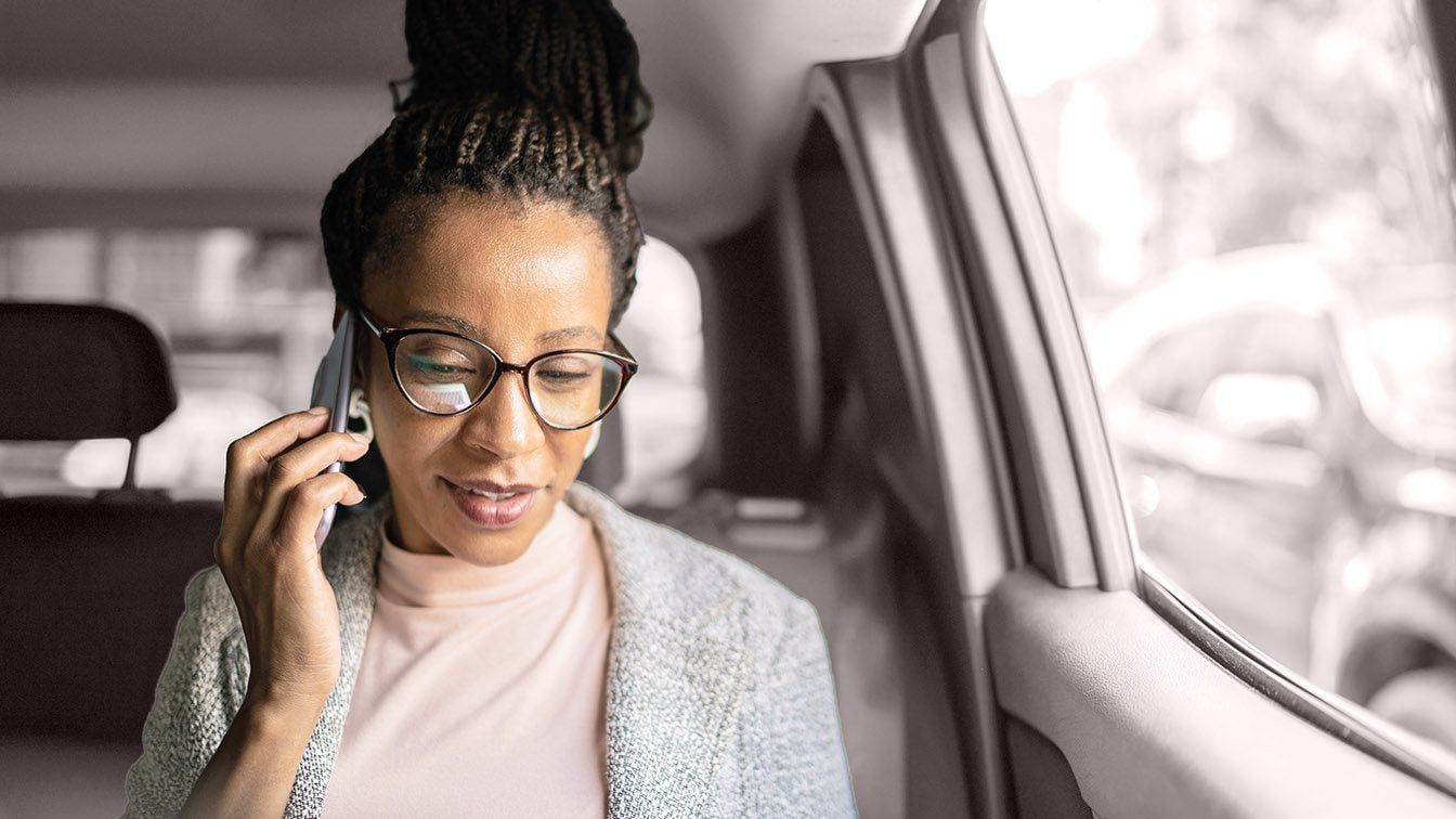 Image of a professional businesswoman speaking on a mobile phone in a car, representing executive leadership, communication, and RHR’s C-suite assessment and leadership advisory services.