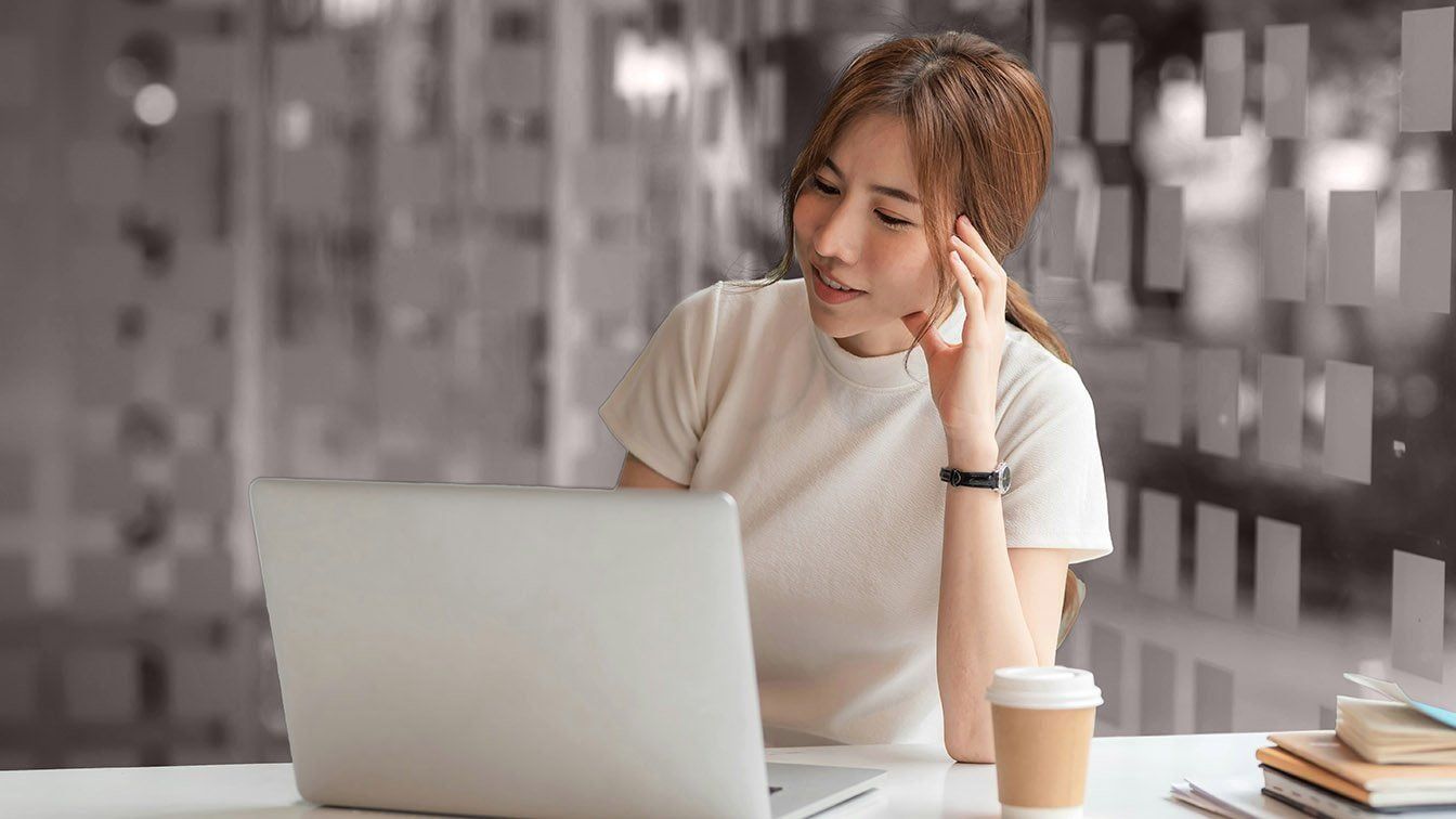 Image of a young professional working on a laptop in a modern office, representing career growth, learning potential, and RHR’s Emerging Talent Solutions.