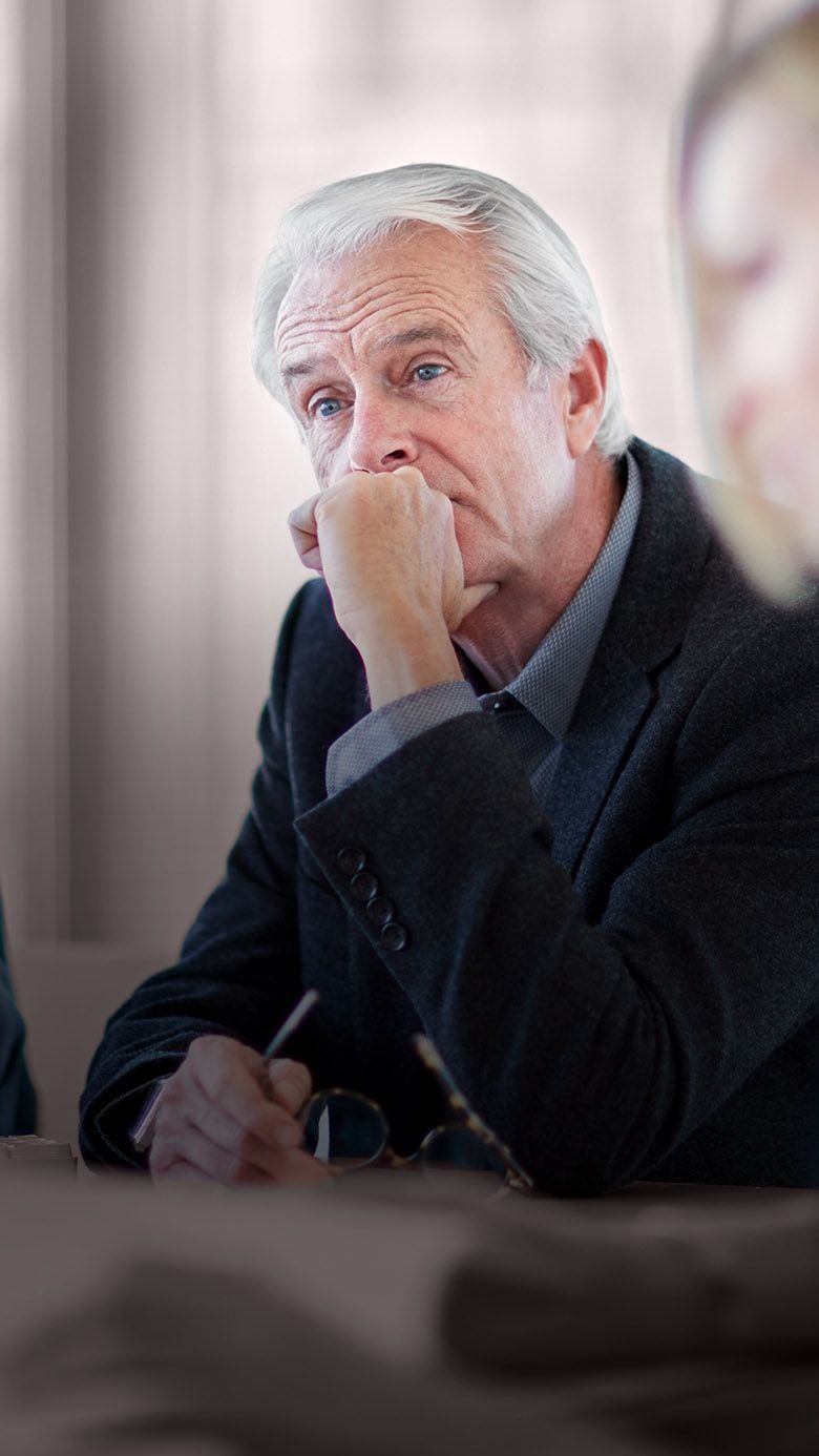 Vertical image of a senior business executive in discussion during a meeting, representing board leadership, governance, and RHR’s Board Evaluation and Development Solutions.