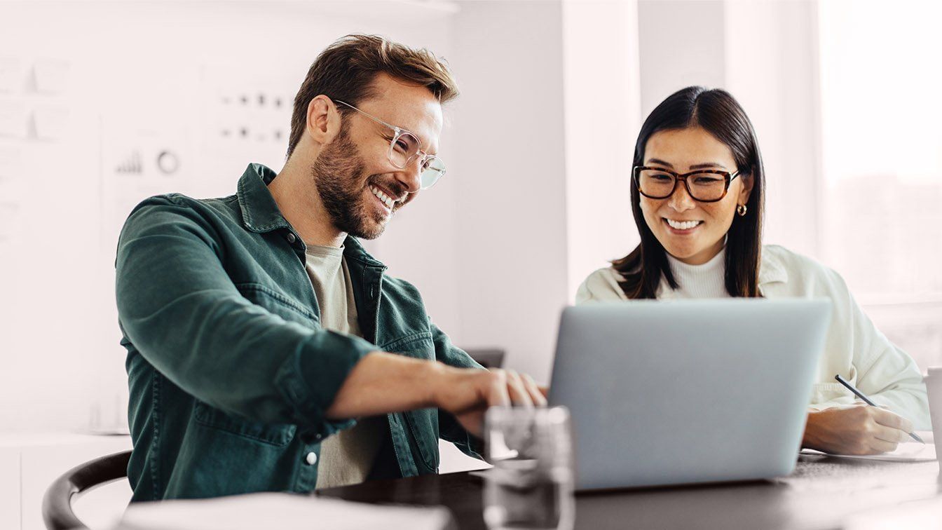 Image of professionals collaborating at a laptop during a meeting, representing executive coaching, leadership development, and RHR’s C-Suite Advisory Coaching Solutions.