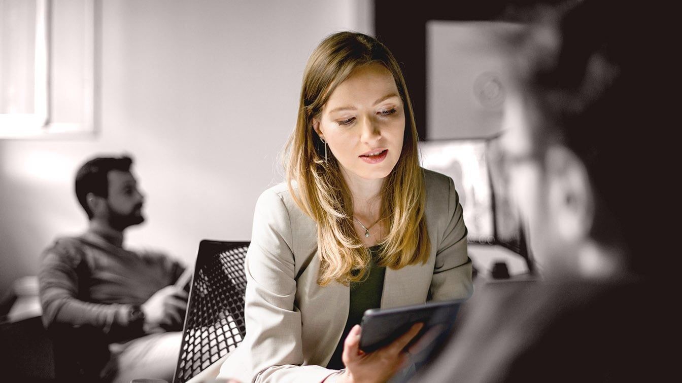 Image of a professional businesswoman reviewing information on a tablet during a meeting, representing leadership growth, executive coaching, and RHR’s Coaching and Development Programs.