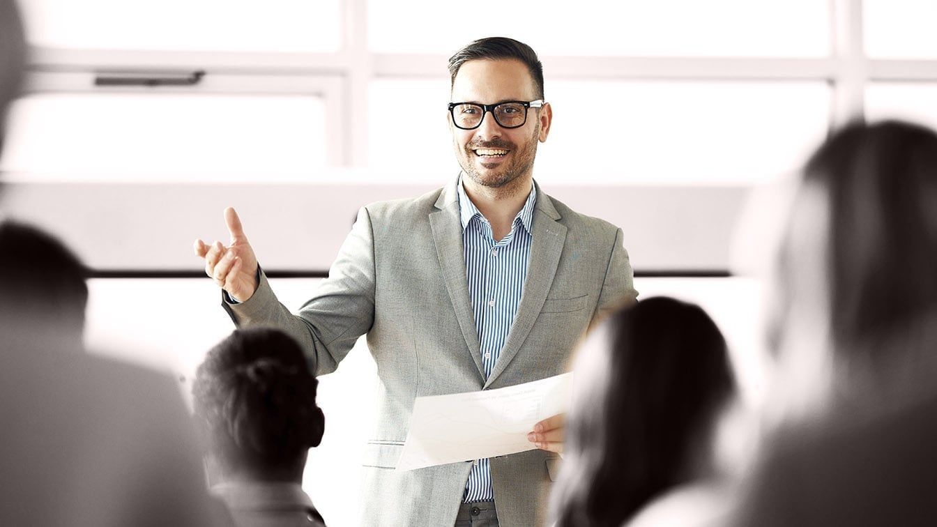 Image of a business leader presenting to a group during a meeting, representing leadership development, communication skills, and RHR’s Leadership Coaching services.