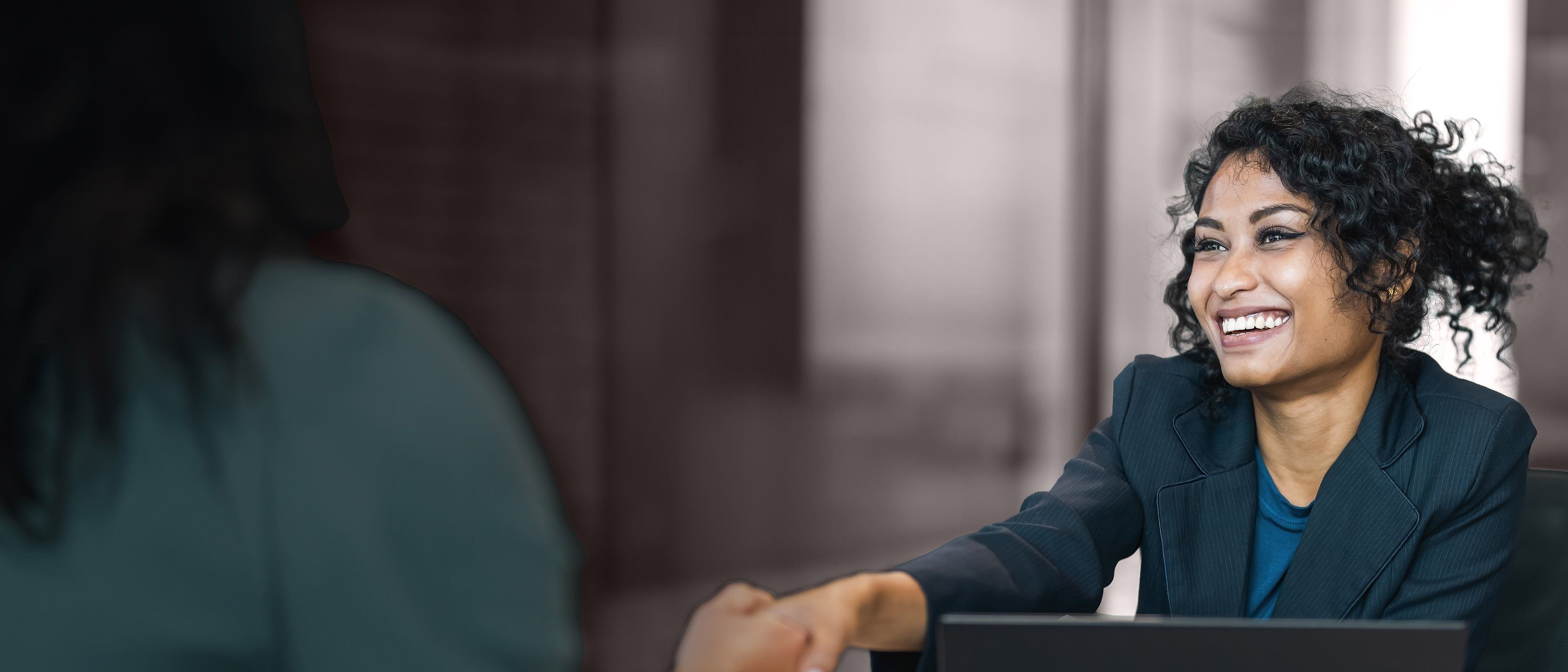 Wide banner image of a business professional greeting a candidate during a meeting, representing executive hiring, leadership selection, and RHR’s External Selection Solutions.