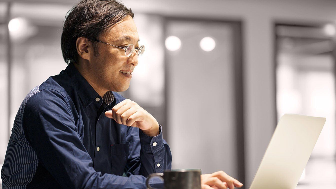 Image of a professional business leader working on a laptop in a corporate setting, representing executive hiring, candidate evaluation, and RHR’s External Selection Solutions.
