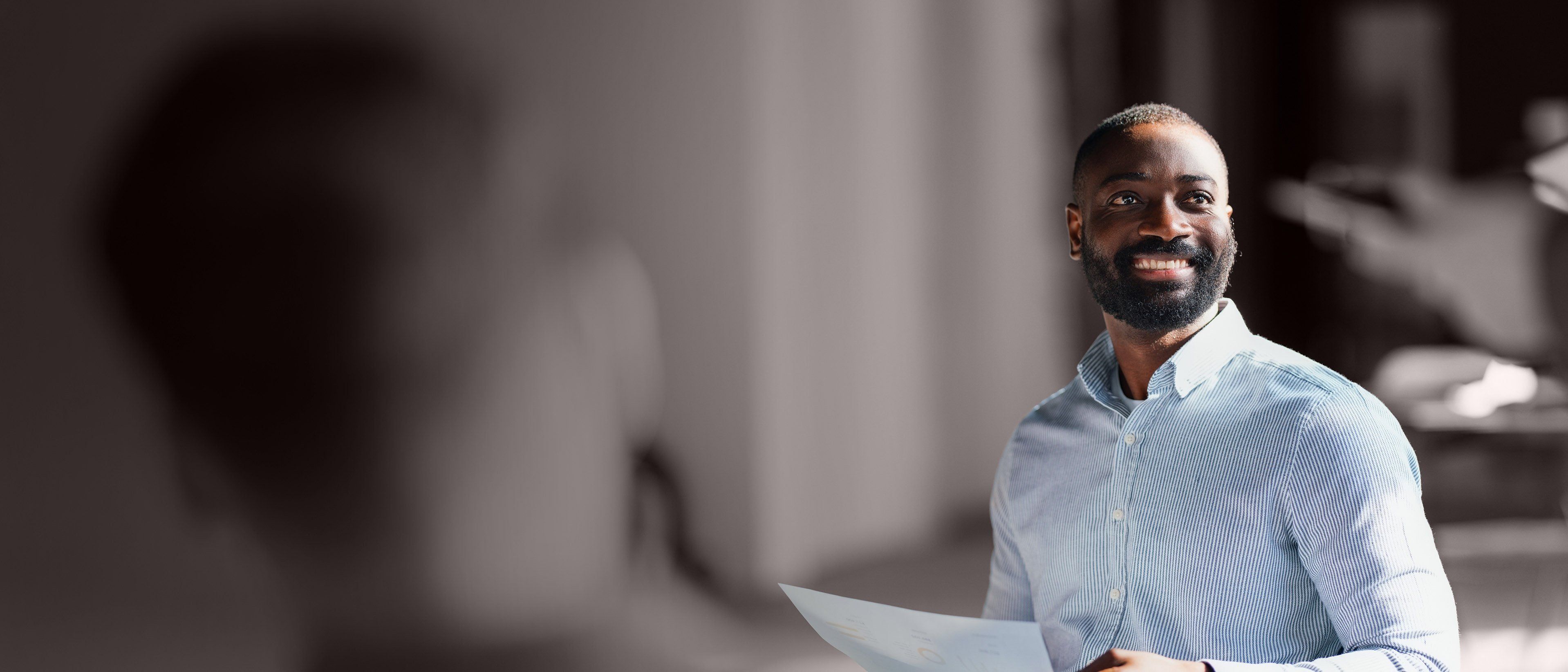 Wide banner image of a business professional holding documents during a meeting, representing leadership advancement, succession readiness, and RHR’s Internal Promotion Solutions.
