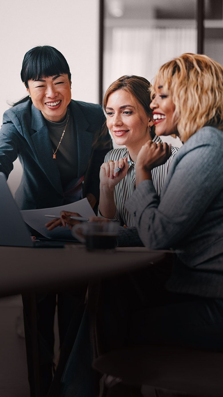 Portrait image of business professionals collaborating around a laptop, representing workforce insights, talent analytics, and RHR’s People Analytics Solutions.