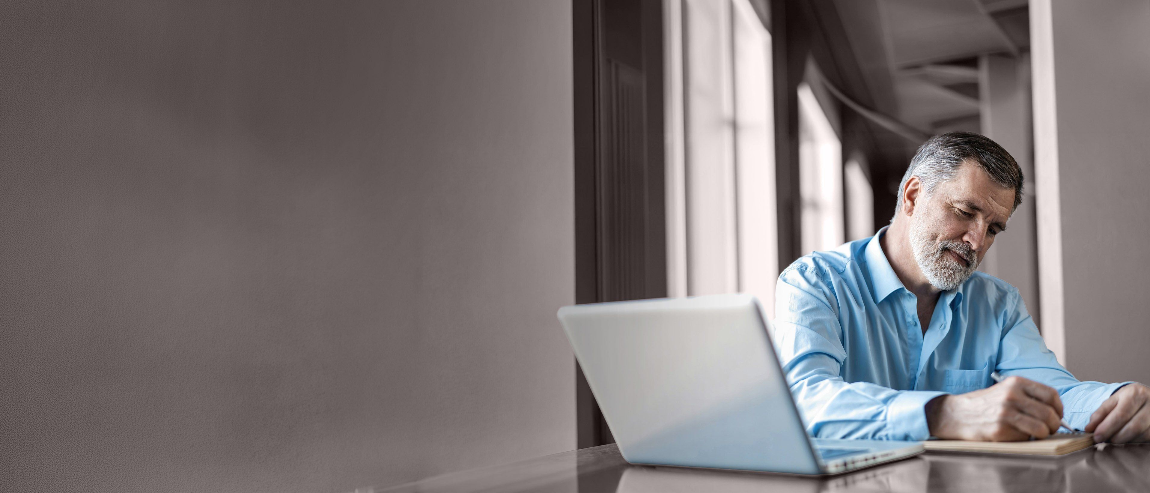 Wide banner image of a business leader reviewing notes beside a laptop, representing leadership evaluation, executive coaching, and RHR’s Strategic Assessment and Coaching Solutions.