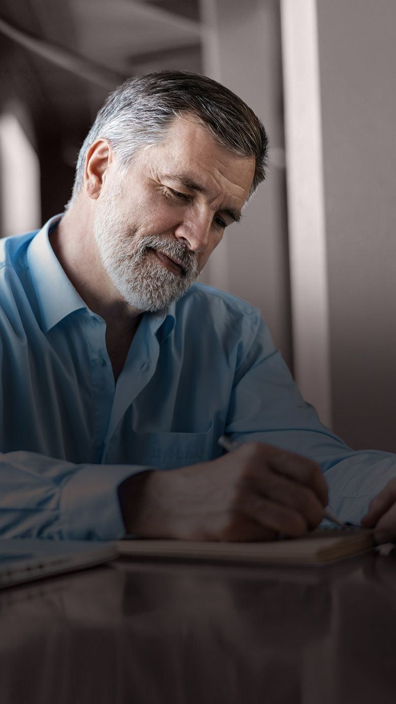 Portrait image of a business leader reviewing notes beside a laptop, representing leadership evaluation, executive coaching, and RHR’s Strategic Assessment and Coaching Solutions.