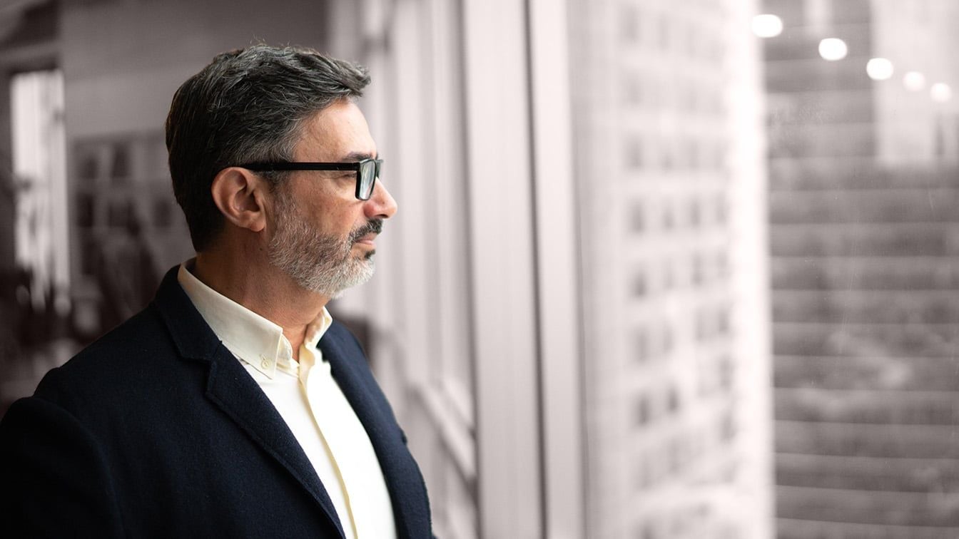 Senior portfolio company executive looking thoughtfully out an office window, reflecting on leadership strategy
