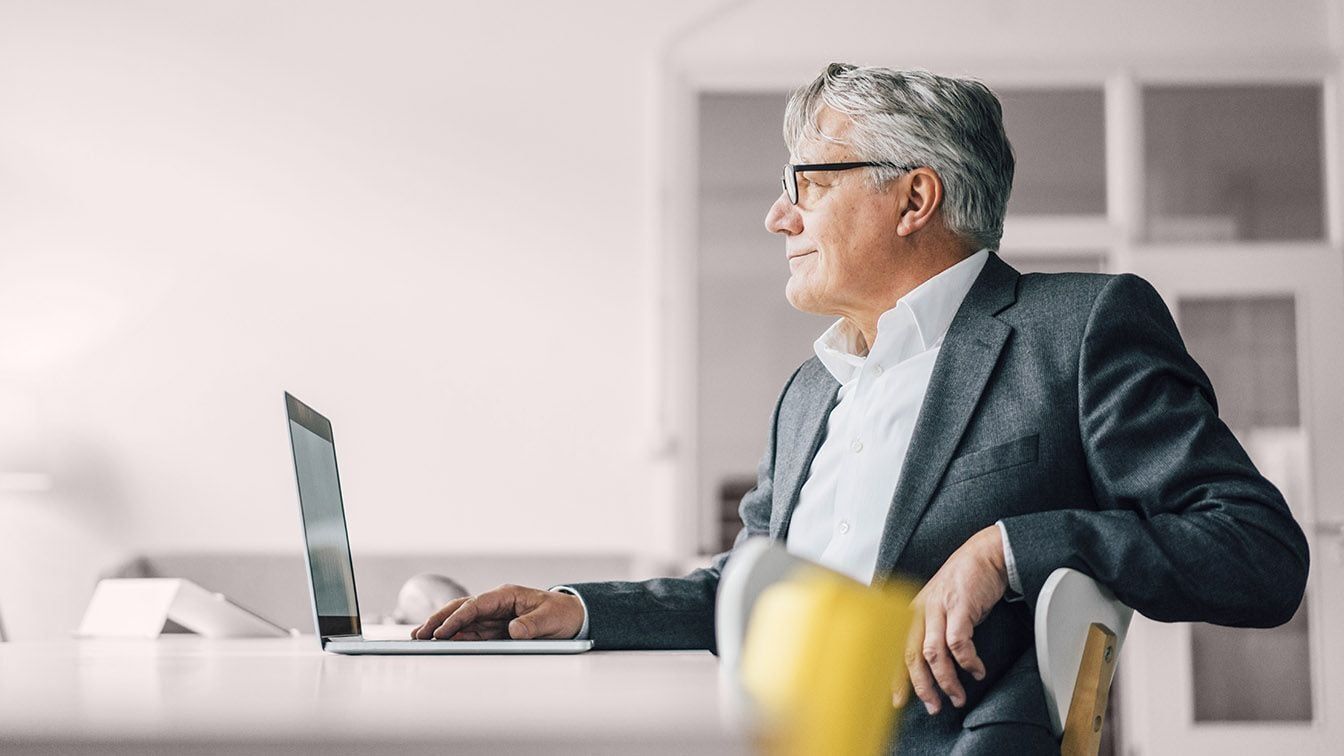 Senior executive reflecting at a desk, representing the leaders, executives, and organizations RHR partners with to strengthen leadership effectiveness, navigate critical transitions, and drive long-term business success.