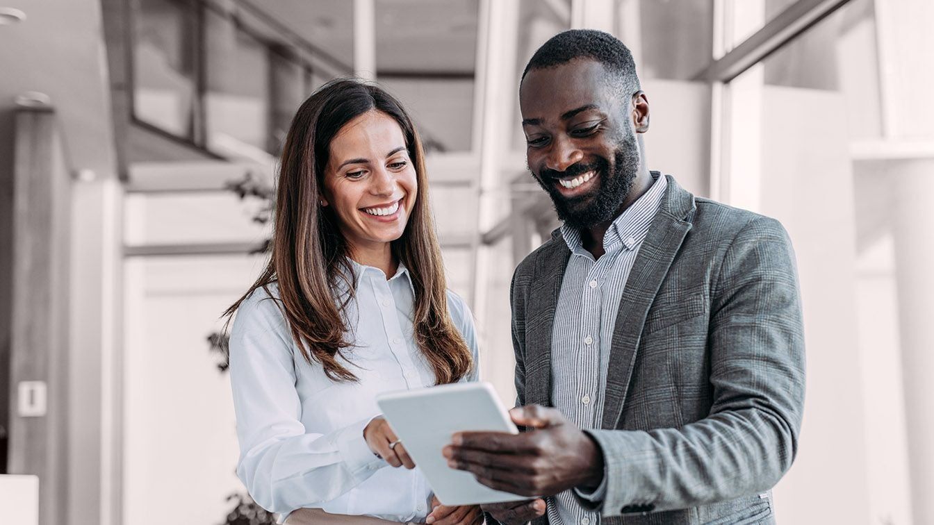 Two professionals reviewing information together on a tablet, representing the executives, leaders, and organizations RHR works with to make informed talent decisions, strengthen leadership capability, and drive business performance.